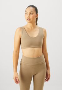 Brown crop top with a scoop neckline paired with high-waisted brown leggings. Smooth texture and snug fit enhance comfort and support.