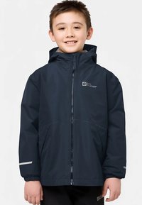 Marinblå vattentät jacka med huva, dragkedja framtill och elastiska muddar. Har en logotyp på bröstet och reflexdetaljer på ärmarna.