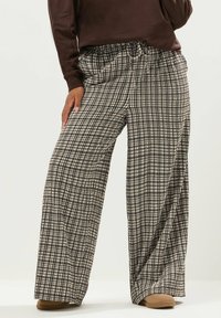 Breda byxor i ett svart och beige rutig mönster, gjorda av lättviktsmaterial med elastisk midja och dragsko.