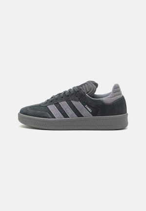 Baskets Adidas Samba gris foncé avec trois bandes gris clair, semelle texturée et design à lacets, vues de côté.
