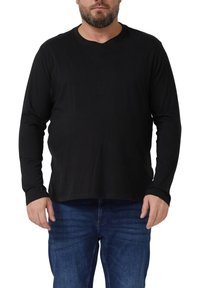 Schwarzes langärmliges Shirt aus weichem, elastischem Stoff mit rundem Ausschnitt und lockerem Schnitt, kombiniert mit blauen Jeans.