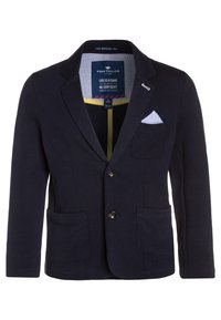 Blazer blu navy in tessuto testurizzato con colletto a punta, due tasche frontali e un fazzoletto bianco. I bottoni sono scuri e rotondi.