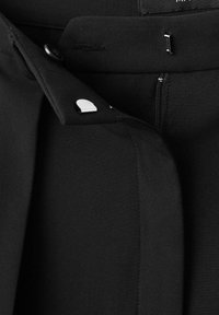 Czarna, dopasowana odzież o smukłym designie, z gładką fakturą, detalami w postaci guzików oraz ukrytym zamkiem z boku.