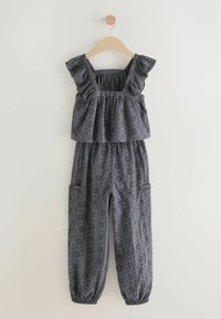 Grå volangbyxdress med hålmönster, som har en figursydd överdel, elastisk midja och två sidofickor. Mjuk tyg, löst sittande ben.