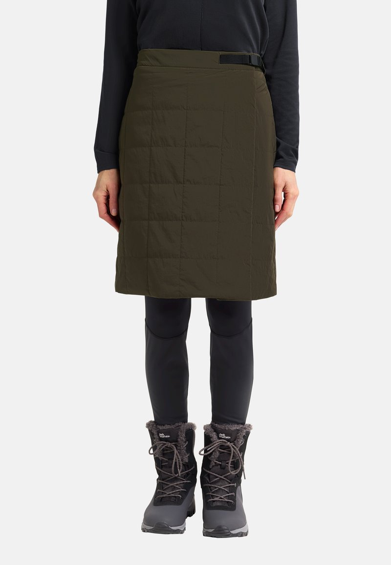 Olijfgroene gequiltte rok met een gladde textuur en zwart riemdetail, gecombineerd met zwarte thermoleggings en met bont gevoerde sneeuwlaarzen.