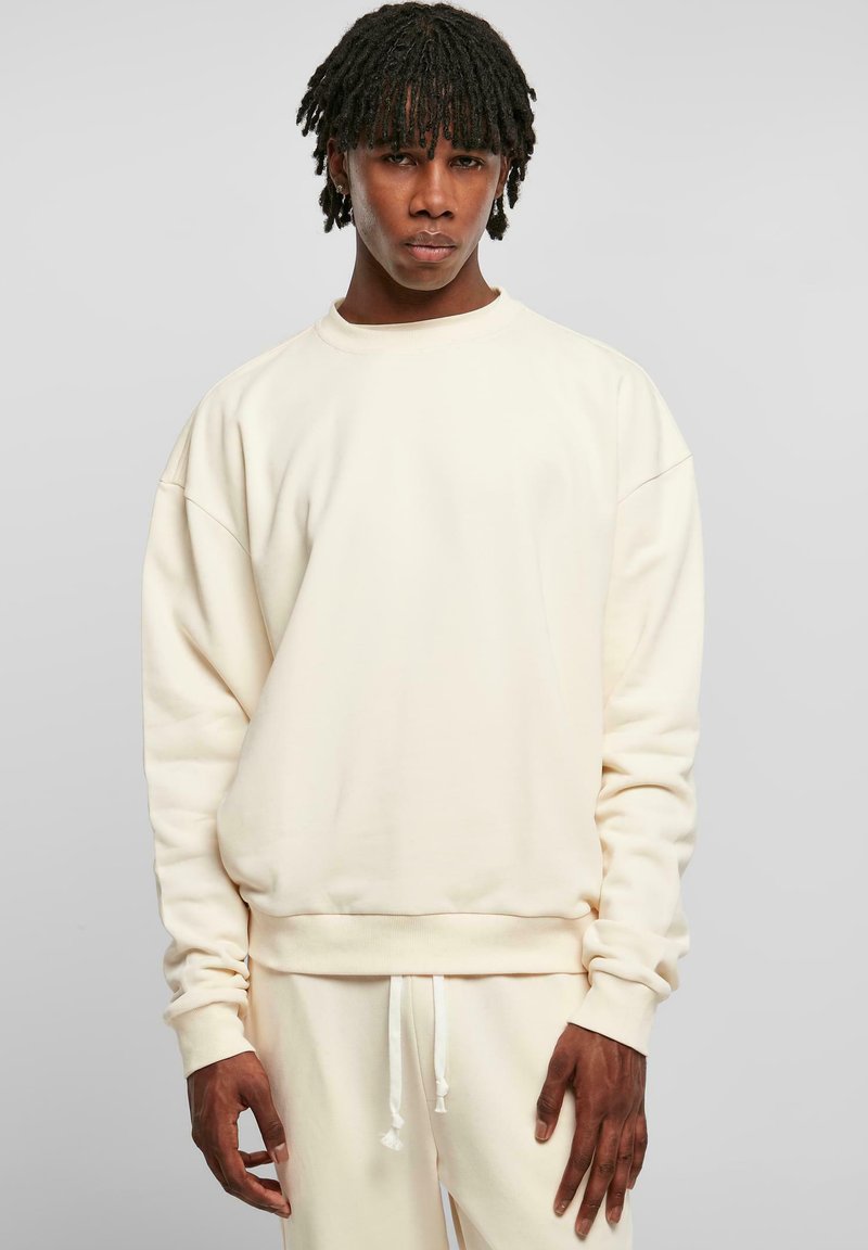 Helles Creme Sweatshirt mit lockerer Passform, gerippten Bündchen und Saum, aus weichem Stoff gefertigt. Kombiniert mit dazu passenden Pants, die ein harmonisches Farbschema betonen.