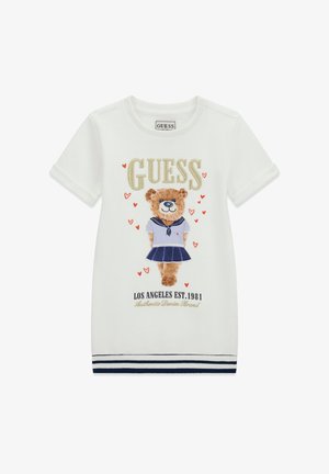 T-shirt en coton blanc avec un motif d'ours en tenue de marin, cœurs décoratifs et lettres dorées. Détail de l'ourlet à rayures marine.