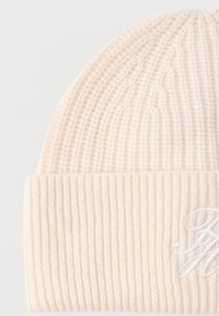 Knit beanie in light cream, featuring ribbed texture and a folded cuff, detailed with white embroidered script on the front.