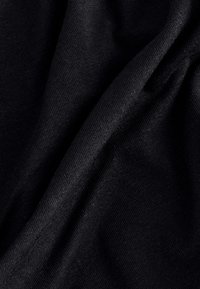 Čierna bavlnená látka s hladkou textúrou, zobrazujúca jemné rebrovanie a mäkké záhyby, naznačujúce pružnosť a jemný pád.