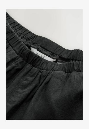 Sort elastisk talje med samlet tekstur, prydet med et tekstillabel syet indeni. Stoffet virker blødt og let.