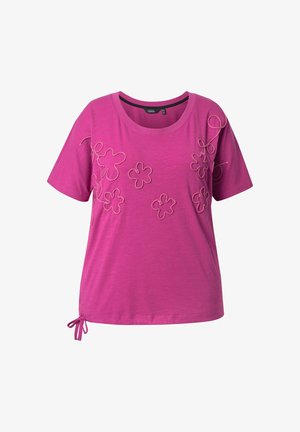 Camiseta rosa de manga corta con diseños bordados florales en varias formas, con un detalle de cordón en el dobladillo. Textura de tela suave.