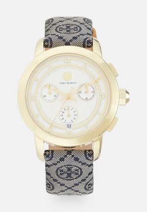 Reloj dorado con esfera blanca, tres subesferas y una ventana para la fecha, con una correa de tela con patrón en azul marino. Diseño de caja redonda.