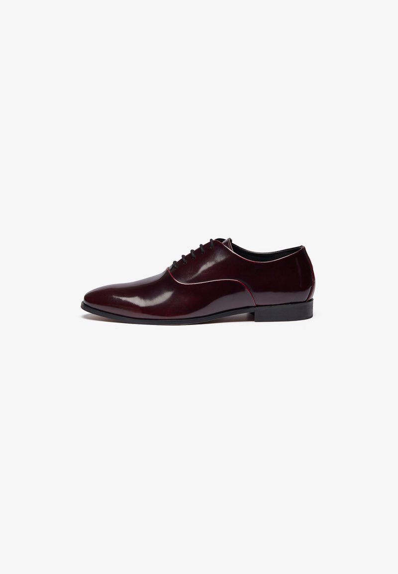 Chaussure de ville en cuir bordeaux avec finition polie, système de laçage, silhouette élégante et petit talon noir.