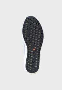 Sulan på skon har ett strukturerat mönster i svart gummi, en vit mellansula och en cirkulär röd detaljpunkt i mitten.