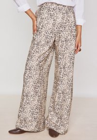 Pantalons larges à motif léopard dans une couleur beige clair, avec un tissu doux, une taille élastique et des poches latérales.