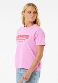 Roze katoenen T-shirt met korte mouwen, voorzien van een rood retro-logo met de tekst "Surfing Company" op de voorkant. Klassiek ontwerp met ronde hals.