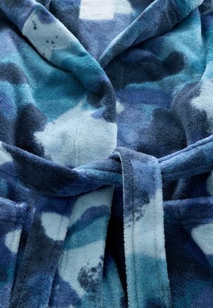 Fleece kopalnica s kapuco, ki ima modro kamuflažno vzorec z različnimi odtenki modre, belimi detajli in crnima pasom. Mehka tekstura.