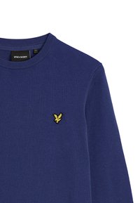 Maglione lavorato a maglia blu navy con collo a giro in rilievo e un piccolo logo di un'aquila gialla ricamato sul lato sinistro del petto.