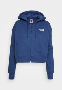 Felpa corta in blu navy, con zip, realizzata in tessuto morbido, con logo frontale, cappuccio grande e polsini a coste; presenta due tasche frontali.