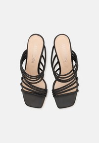 Des sandales noires à talon ouvert avec plusieurs lanières tressées, un bout carré, une semelle intérieure en cuir lisse et un design minimaliste.