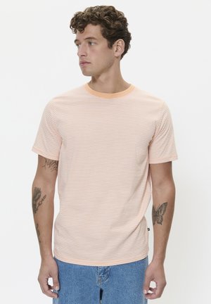 Striped short-sleeve t-shirt with an orange and white pattern, round neckline, and soft texture. Worn with light blue denim shorts.