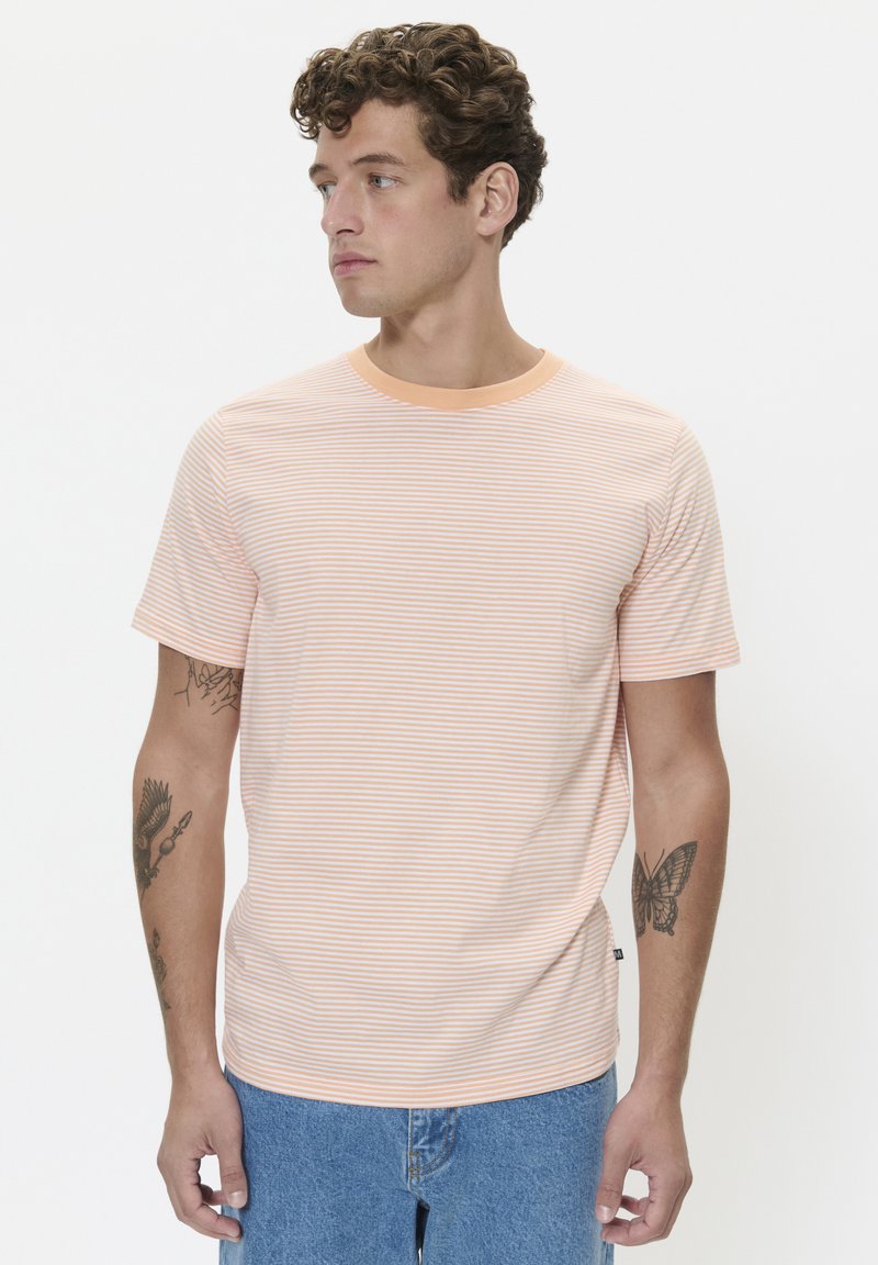 Striped short-sleeve t-shirt with an orange and white pattern, round neckline, and soft texture. Worn with light blue denim shorts.