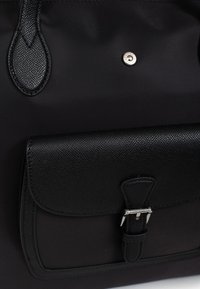 Borsa tote nera in nylon con tasca in pelle strutturata. Caratterizzata da una chiusura a pressione in argento e dettagli in pelle sulle maniglie.
