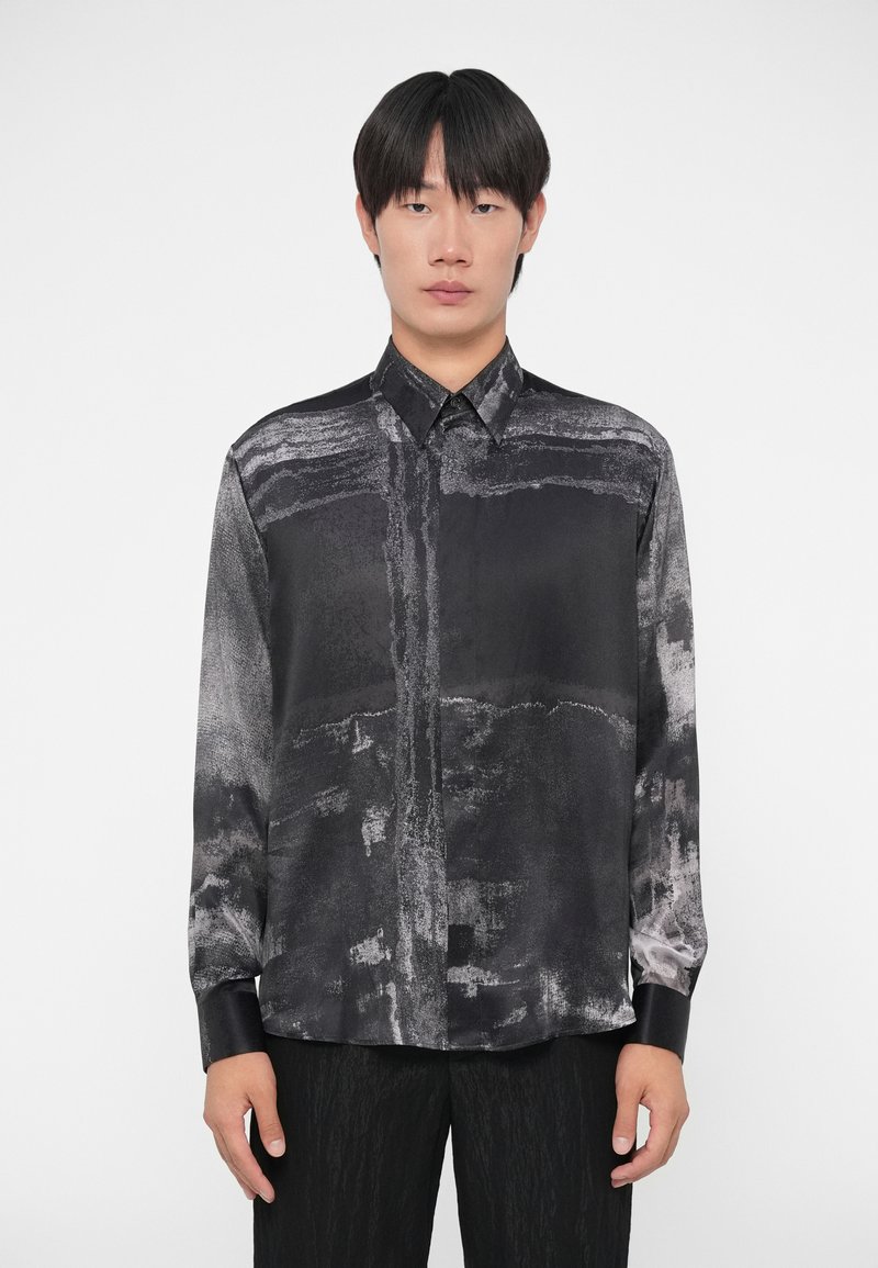 Langarmshirt in zwart en grijs met abstracte patronen, ontworpen met een kraag en glanzende textuur. Zachte stof valt soepel.