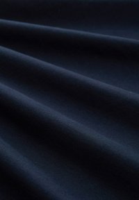 Marineblauwe stof met een gladde textuur, getoond in plooien. Het materiaal lijkt zacht en lichtgewichtig, met een lichte glans.