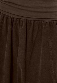 Brautobermaterialrock aus cord gefertigt, mit gerafftem Bund und glatter oberer Schicht, vertikaler Rippstruktur und mittlerer Länge.