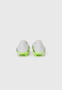 White soccer cleats with a textured surface, green accent on the sole, black detailing, and a low-cut design. Viewed from the back.