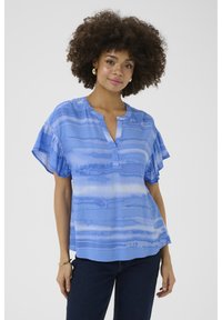 Zila rakstota blūze ar brīvu piegriezumu, īsām volānu piedurknēm un izgriezumu V-veida formā. Iezīmē horizontālas svītras dažādās zila toņās.