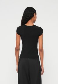 Fekete rövid ujjú póló kerek nyakkivágással, puha anyagból, testhezálló kialakítással, hátulnézetben.