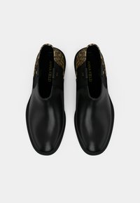 Černé kožené kotníkové boty s hladkým povrchem, které mají leopardí potisk na límci a elastické boční panely pro snadné obouvání.