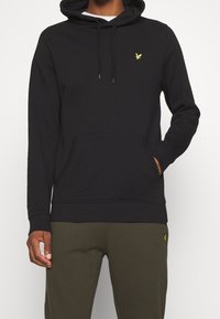 Felpa nera con cappuccio realizzata in tessuto morbido, dotata di tasca a kangaroo, cappuccio regolabile con lacci e un piccolo logo giallo sul petto.