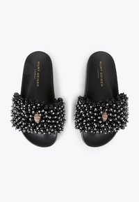 Zwarte slippers met een gestructureerde leren band versierd met fonkelende accenten. Voorzien van een gladde zwarte zool. Merkenlogo zichtbaar aan de binnenkant.