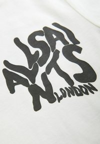 Texte noir déformé indiquant "AllSaints London" sur une surface en tissu blanc, probablement un gros plan d'un vêtement.