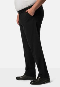 Černé kalhoty se střihem rovného nohavice, dvěma bočními kapsami a zapínáním na knoflík. Nosí se s přiléhavým bílým topem a černými botami.