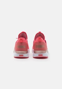 Zapatillas de running Puma con una parte superior de malla rosa, talón texturizado, acentos metálicos dorados y una suela blanca acolchada.