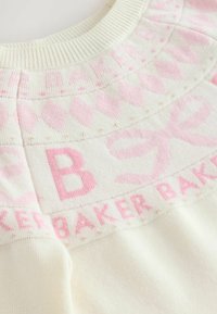 Suéter de punto color crema con un patrón de diamantes rosa, lazos y el texto "BAKER" repetido a lo largo del escote.