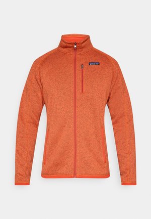 Fleecejakke i lys orange med høj krave, fuld lynlås og kontrasterende orange detaljer. Har sidelommer og en brystlomme med lynlås.