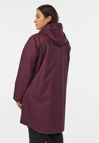 Chaqueta marrón waterproof con capucha. Presenta un patrón floral, mangas largas y un corte recto. Textura suave, diseño para exterior.