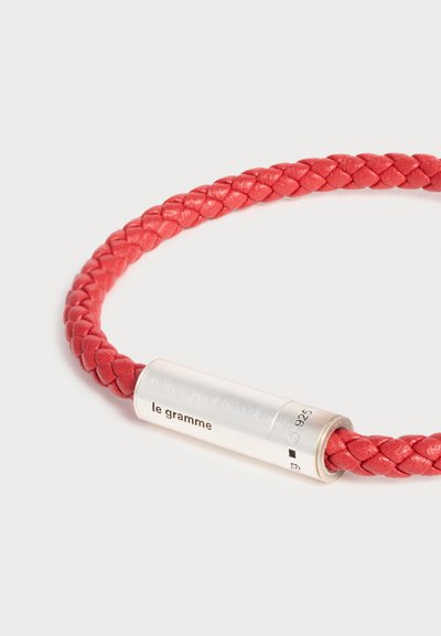 Bracelet en cuir rouge tressé avec fermoir cylindrique en argent gravé "le gramme" et poinçons de pureté du métal.
