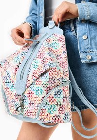 Sac à dos tissé coloré avec un motif géométrique, des accents en cuir bleu clair, une double fermeture éclair et des sangles réglables.