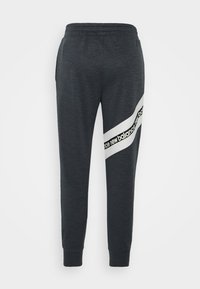 Mörkgråa sweatpants i mjukt material, med ett snedvridet vitt rand med svart "new balance"-logotyp på vänster ben. Elastisk midja.