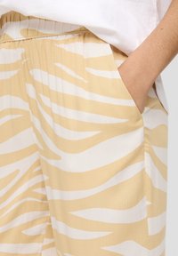 Loungewear shorts in een lichtgele kleur met witte zebra strepen. Voorzien van een elastische tailleband en zijzakken, gemaakt van lichtgewicht stof.