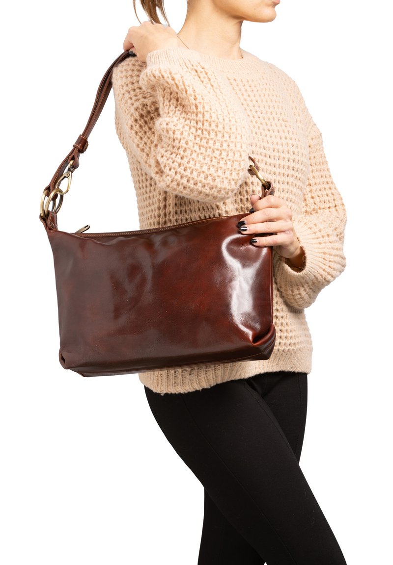 Sac à main en cuir marron avec une texture lisse, fermeture éclair et une courte bandoulière réglable. Présente des accessoires en hardware doré.