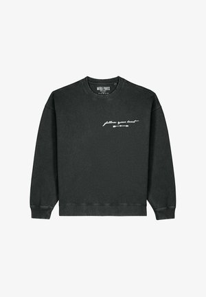 Felpa nera con scollo a girocollo e polsini a coste. Presenta una scritta bianca in corsivo "follow your heart" e un piccolo disegno di una freccia.