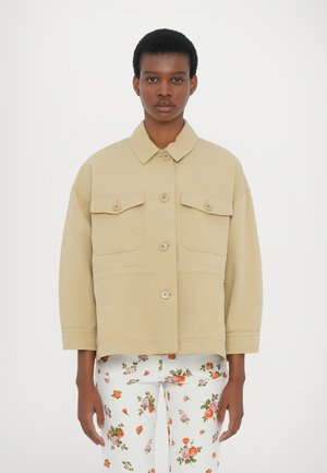 Beige jacket with a collar, four front pockets, and button closure, paired with floral patterned white pants featuring orange and pink flowers.