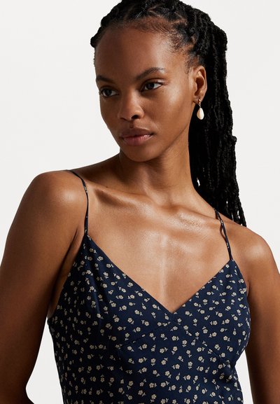 Navy blue floral dress with thin straps and V-neckline; features small white flower pattern; worn with a teardrop earring.